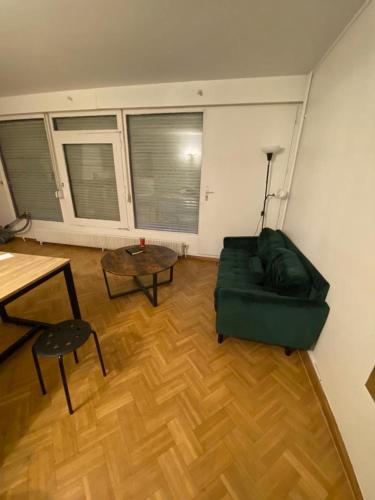 ein Wohnzimmer mit einem grünen Sofa und einem Tisch in der Unterkunft La singulière in Cergy