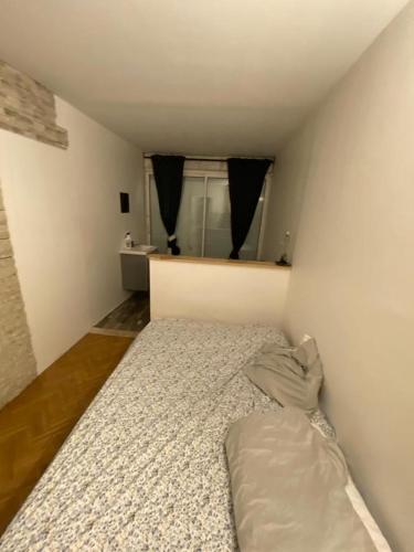 ein kleines Schlafzimmer mit einem Bett in der Ecke in der Unterkunft La singulière in Cergy
