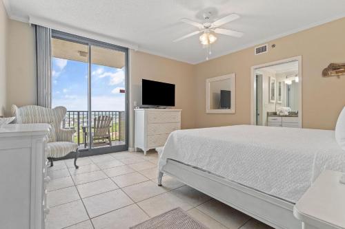 a bedroom with a bed and a television and a balcony at Phoenix VIII 1406 in Orange Beach