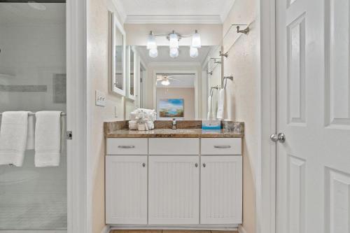 a white bathroom with a sink and a mirror at Phoenix VIII 1406 in Orange Beach