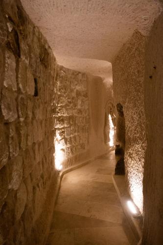 a cave with a stone wall and a person with lights at Vigor Cappadocia - Special Class in Uchisar