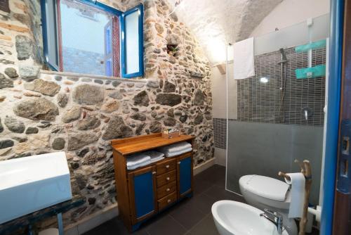 a stone walled bathroom with a toilet and a sink at U Catoiu in Scilla
