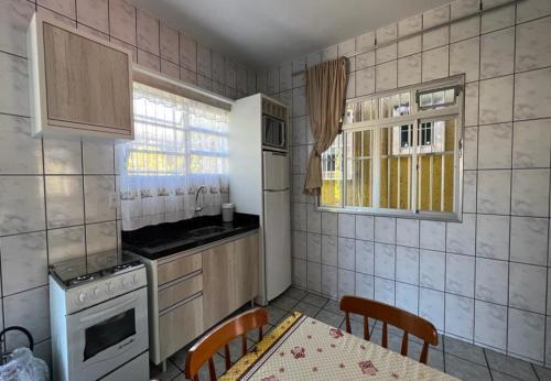 uma cozinha com uma mesa, um fogão e uma janela em Recanto do Martins em Florianópolis