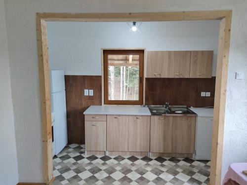 an empty kitchen with wooden cabinets and a window at Vukov Konak - Wolf's lodge in Žabljak