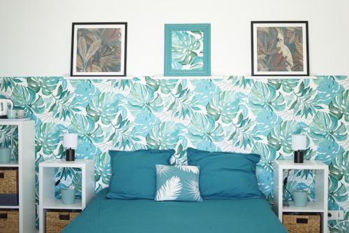 1 dormitorio con cama azul y papel pintado con motivos florales en Les Volets Bleus en Spéracèdes