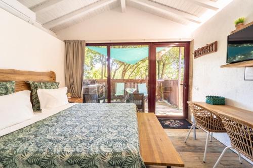 1 dormitorio con cama, mesa y balcón en Casas Casal Do Carvalhal - Agroturismo, en Amares