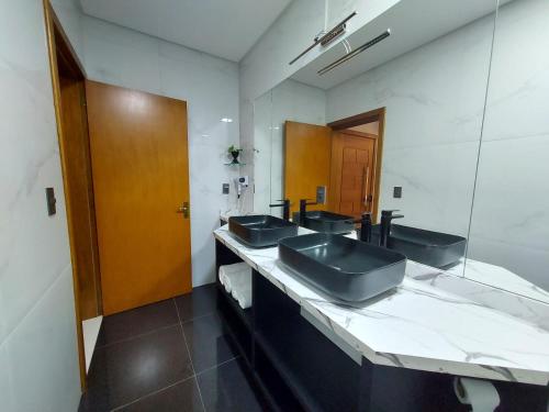 een badkamer met 3 wastafels en een grote spiegel bij Pousada San Doná in Bento Gonçalves