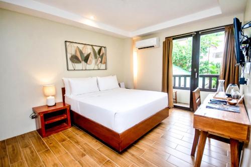 a bedroom with a bed and a desk and a window at Serene La Playa Boracay in Boracay