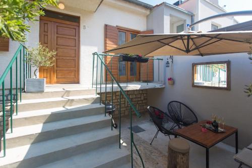 un patio con una mesa y una sombrilla en Holiday house VIDA, en Biograd na Moru