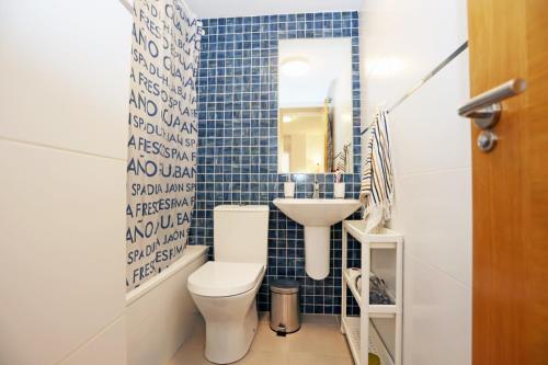 een blauw betegelde badkamer met een toilet en een wastafel bij Casa Fenicia - Cosy apartment with free private parking in Málaga