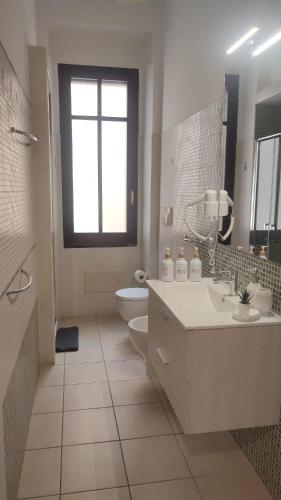a bathroom with a sink and a toilet and a window at Sa domu de su beciu in Cagliari