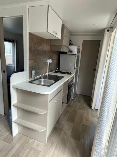 a small kitchen with a sink and a refrigerator at Mobil home en camping 4 étoiles à Bonne Anse Plage / La Palmyre in Les Mathes