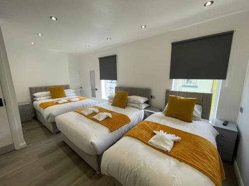 a bedroom with three beds with yellow and white sheets at Araan House Hotel -Families and Couples Only in Blackpool