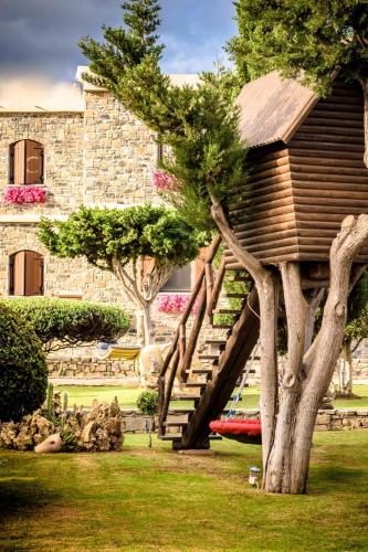 a house with a wooden staircase next to a tree at Nectar luxury apartments in Sitia