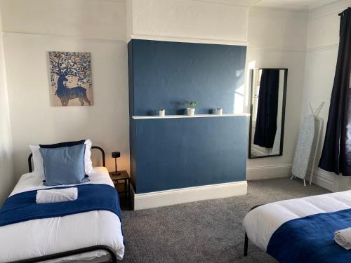1 dormitorio con 2 camas y pared azul en Overhill - Spacious 2 bed ground floor flat close to Newcastle, en Gateshead