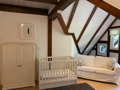 a white crib in a room with wooden ceilings at Berghof Schmitte in Winterberg