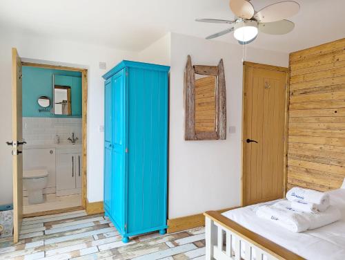 Schlafzimmer mit einem blauen Schrank und einem Badezimmer in der Unterkunft Seaside in Selsey