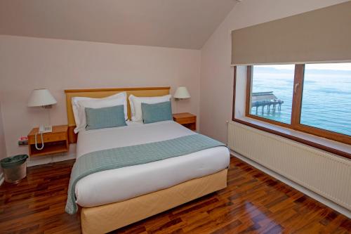 um quarto com uma cama grande e uma janela grande em Gran Hotel Vicente Costanera em Puerto Montt