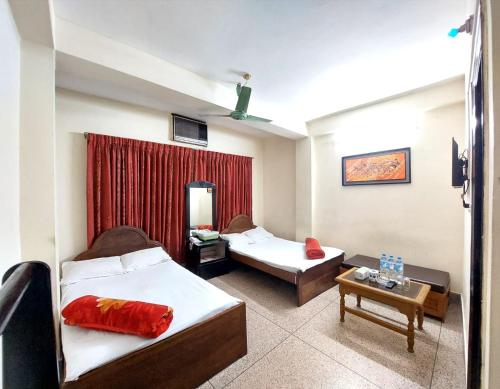 a hotel room with two beds and a table at Hotel Hoque Tower International in Chittagong