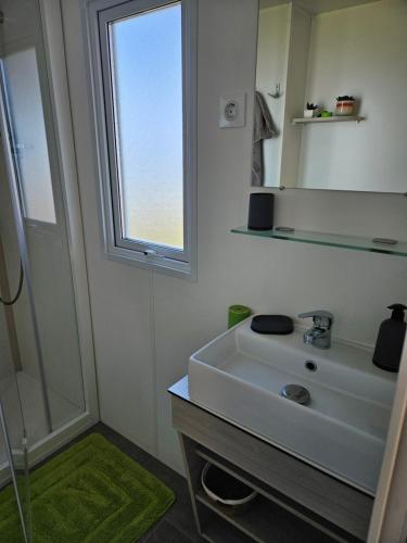 baño con lavabo, espejo y ventana en Mobilhomme LECCI 3 CHAMBRES AVEC VUE MER EXCEPTIONNELLE en Lumio