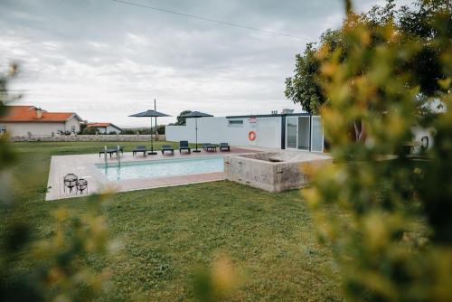 una piscina con bancos y sombrillas en un patio en Sete Azenhas en Esposende