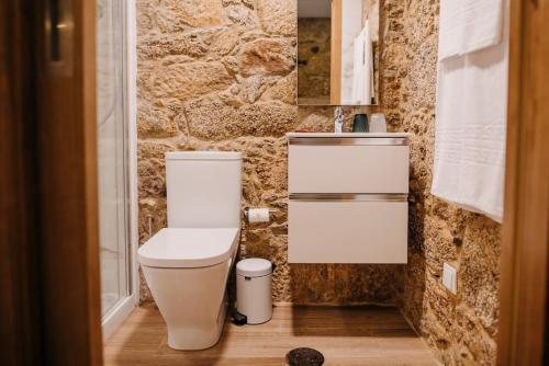 baño con aseo blanco y pared de piedra en Sete Azenhas en Esposende