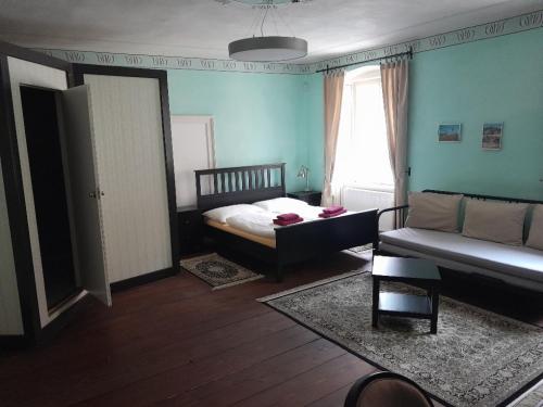 a bedroom with a bed and a couch and a window at Klášterní apartmány in Český Krumlov