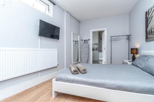 a white bedroom with a bed and a tv at Modern Apartment in East London in London