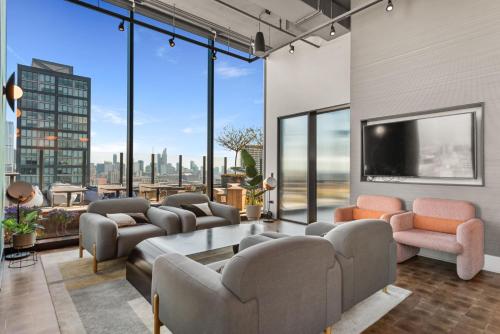 a living room with couches and a tv and large windows at Avra Stylish Apartments Prime West Loop Location Near Union Park in Chicago