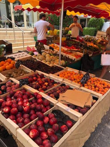 un marché avec des caisses de pommes et d'autres fruits et légumes dans l'établissement Grand Studio véranda et terrasse, à Carqueiranne