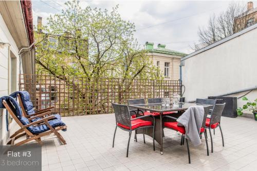eine Terrasse mit einem Tisch und Stühlen auf dem Balkon in der Unterkunft Dandelion Apartments Lāčplēša in Riga