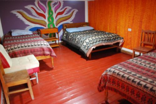 a bedroom with two beds and a colorful wall at Hospedaje La Ñusta in Ollantaytambo