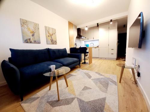 a living room with a blue couch and a table at NeoApartments Lotnicza in Wrocław