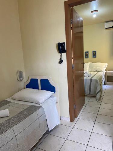 a bedroom with two beds and a tv on the wall at Pousada Maré Mar in Garopaba