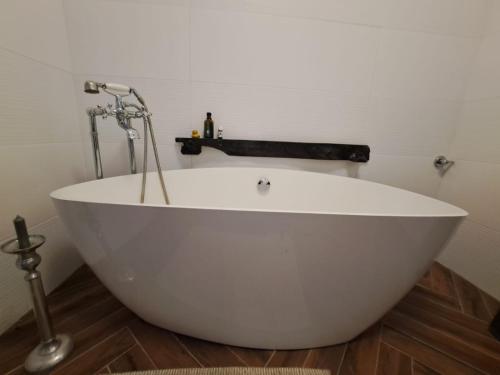 a white bath tub sitting on a wooden floor at @gatetothewild in Coreglia Ligure