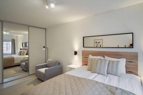 um quarto com uma grande cama branca e uma cadeira em Norden Homes Turku Central 2-Bedroom Apartment em Turku