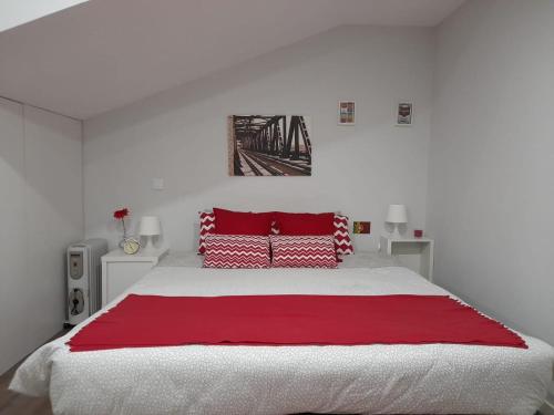 a white bedroom with a large bed with red pillows at Casa Pirosa in Aveiro