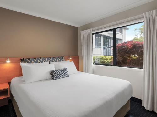 a bedroom with a large bed and a large window at JetPark Hotel Rotorua in Rotorua