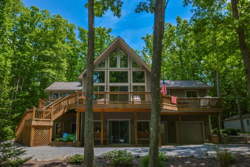a house in the woods with a wrap around deck at Keep Calm and Lake On in Swanton