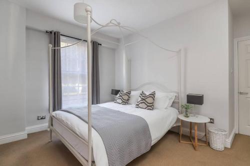 a white bedroom with a canopy bed and a table at No 2 The Old School House, Winchester in Winchester