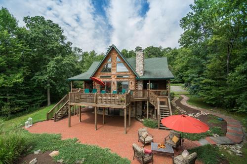 a log cabin with a large deck and an umbrella at Altitude Adjustment in McHenry