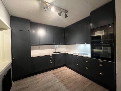 una cocina con armarios negros y encimeras blancas en Storgata 5, en Berlevåg