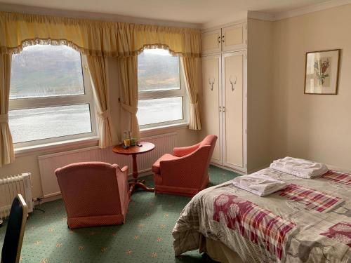 a bedroom with two chairs and a bed and two windows at Lochalsh Hotel with Views to the beautiful Isle of Skye in Kyle of Lochalsh