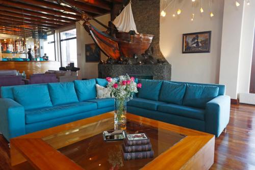 a blue couch in a living room with a vase of flowers at Gran Hotel Vicente Costanera in Puerto Montt