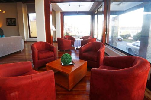 a waiting room with red chairs and a table at Gran Hotel Vicente Costanera in Puerto Montt