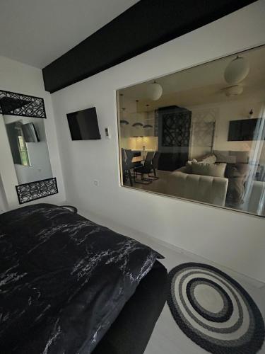 a bedroom with a large mirror and a living room at Sandev apartments Black&White in Štip