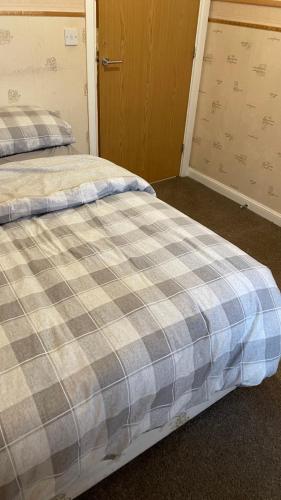 a bed in a room with a plaid at Harper Close in West Thurrock