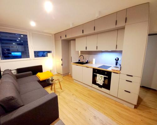 a living room with a couch and a kitchen at NeoApartments Lotnicza in Wrocław