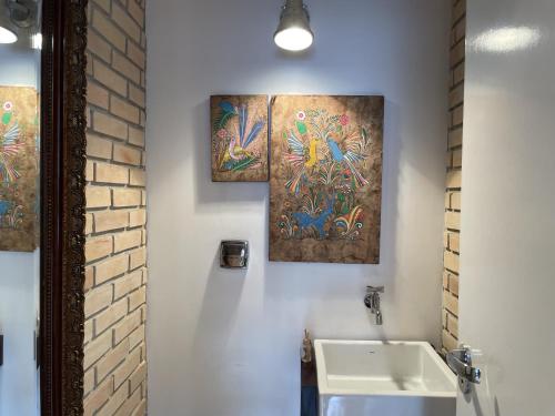 uma casa de banho com duas pinturas na parede e um lavatório em Akile Parque Aclimacao em São Paulo