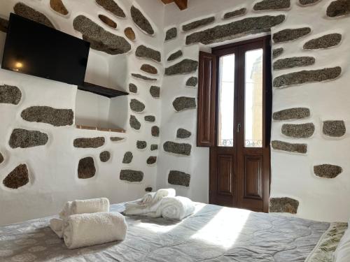 ein Schlafzimmer mit einem Bett in einer Steinmauer in der Unterkunft La Corte Dei Baroni in Loceri